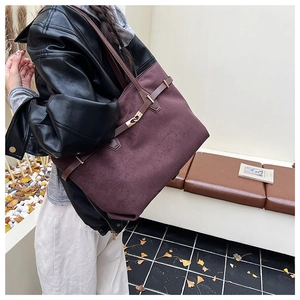 Gros plan sur le sac cabas en daim violet foncé avec fermoir doré et lanières en cuir