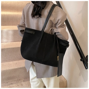 Detail of black suede tote bag featuring slim shoulder straps and matching zipper pouch