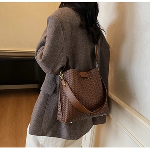 Détail du sac cabas en cuir tressé marron foncé avec large bandoulière et crochets dorés
