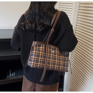 Detail of vintage plaid tote bag with brown leather straps and small cartoon embroidery