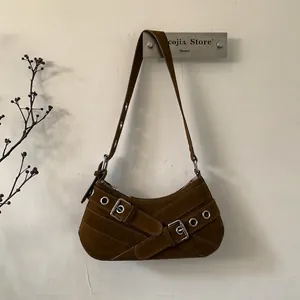 Detail view of brown suede underarm bag with silver metal eyelets and buckle straps