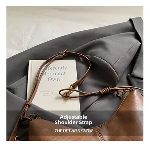 Detail of a brown leather tote bag showing the adjustable strap and gold metal ring