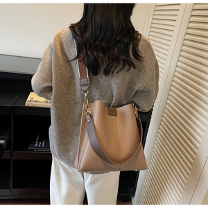Vue arrière du sac seau en cuir marron avec large bandoulière sur modèle femme