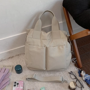 Detail view of off-white nylon tote bag with functional utility pockets and wide handles