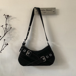 Macro shot of black suede underarm bag with silver grommets and buckle details
