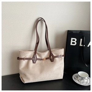 Gros plan détaillé du cabas en daim beige avec anses en cuir marron et boucle dorée
