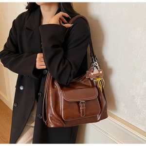 Close-up of brown PU leather tote bag with vintage finish and cute bear keychain detail
