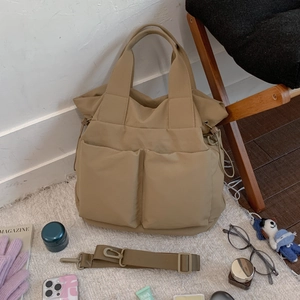 Detail view of khaki nylon tote bag with large front pockets and adjustable shoulder strap