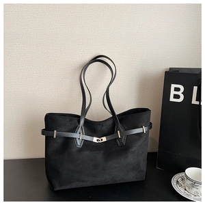 Détail du sac cabas en daim noir avec de fines anses en cuir et un fermoir en métal doré chic