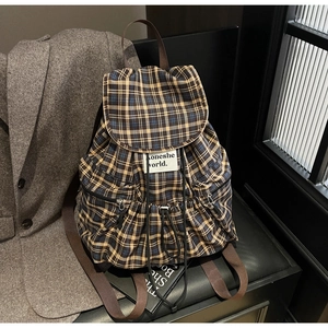 Detailed view of the yellow plaid backpack featuring a drawstring flap and brand label