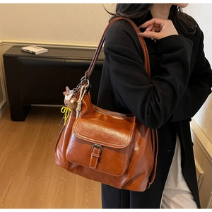 Close-up of vintage brown leather tote bag featuring a front pocket with metallic buckle