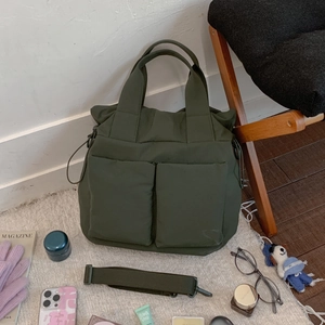 Close-up of olive green nylon tote bag with dual front pockets and adjustable strap