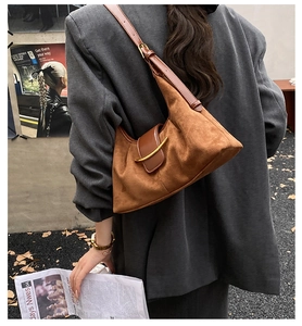 Sac hobo en daim marron avec boucle dorée présenté dans un décor de mode urbaine