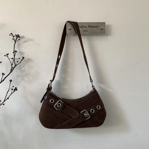 Detail of dark coffee suede underarm bag with metal eyelets and adjustable buckle straps