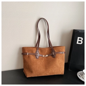 Détail d'un sac cabas en daim caramel avec lanières en cuir marron et boucle dorée