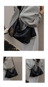 Detail of black leather crescent tote bag with adjustable strap and leopard charm