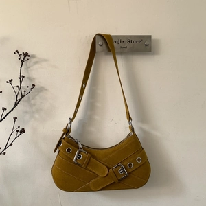 Detail of hobo bag in mustard yellow suede with silver eyelets and buckle accents