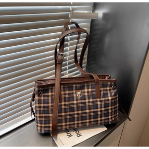 Detail of checkered tote bag featuring a cute bear embroidery and leather straps