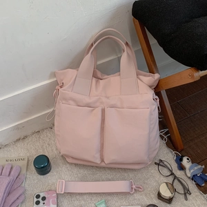 Detail of pink large nylon tote bag with front pockets and adjustable shoulder strap