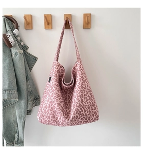 Détail du sac cabas en toile à imprimé léopard rose avec étiquette tissée latérale