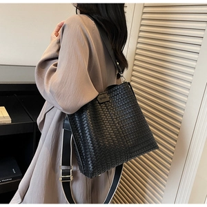 Détail du grand sac cabas noir tressé avec bandoulière large et boucles en métal doré