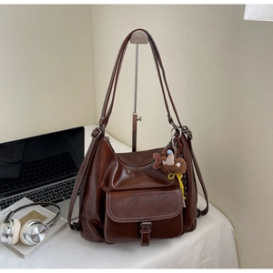 Close-up of retro brown faux leather tote bag with buckle pocket and cute bear pendant