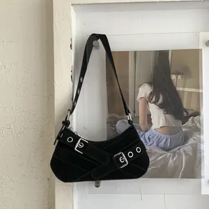 Detail of black suede underarm bag with decorative straps and silver metal buckles