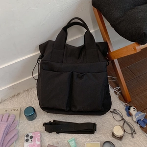 Close-up of black nylon tote bag with multi-pocket design and adjustable strap
