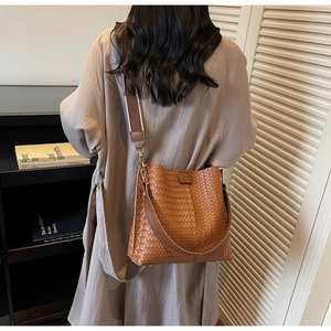 Vue détaillée du dos d'un sac seau en cuir tressé marron avec une large bandoulière