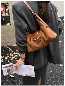 Détail du sac bandoulière en daim caramel avec boucle dorée dans un décor urbain chic