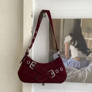 Detailed macro view of burgundy suede crescent bag with metallic eyelets and rocker style