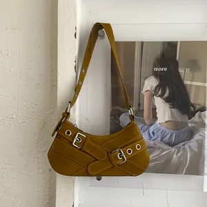 Detail of mustard yellow suede underarm bag with silver buckles and hardware