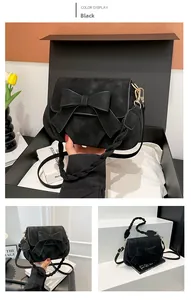 Détails du sac selle noir avec nœud, bandoulière tressée et coffret cadeau