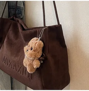Detail der dunkelbraunen Totebag aus Wildlederimitat mit Prägung und Plüsch-Anhänger