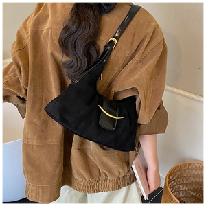 Détail du sac porté épaule noir mat avec boucle en métal doré sur une veste marron chic
