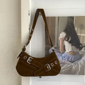 Detail of dark brown suede underarm bag featuring silver eyelets and Y2K biker straps
