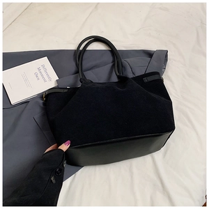 Gros plan sur le sac cabas noir montrant la texture suédée et le détail en cuir