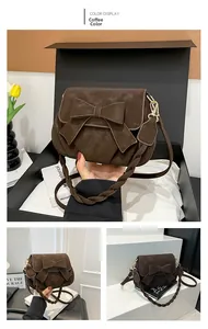 Vue détaillée du sac selle marron café avec nœud et poignée tissée sur boîte cadeau