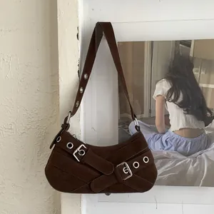 Detail of dark brown suede underarm bag featuring silver buckles and eyelet straps