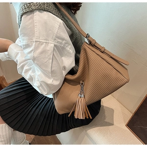 Detailaufnahme der braunen Cord-Schultertasche mit Fransenquaste und diagonaler Streifenstruktur