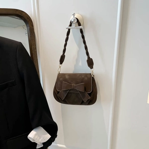 Détail du sac bandoulière en daim marron avec grand nœud et bandoulière tissée