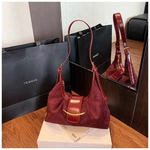 Détail du sac bandoulière bordeaux en daim avec boucle dorée et reflet dans le miroir