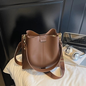 Vue détaillée du grand sac seau marron avec bandoulière large et boucles dorées