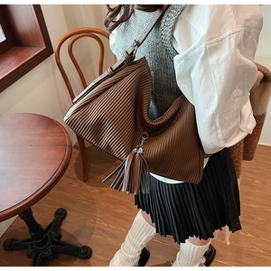 Detailansicht einer dunkelbraunen Cord-Schultertasche mit elegantem Quasten-Anhänger