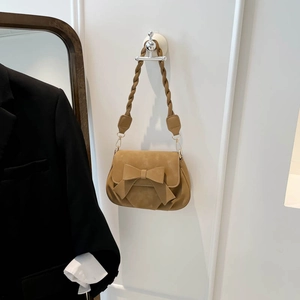 Détail du sac carré camel avec un grand nœud décoratif et une bandoulière tressée