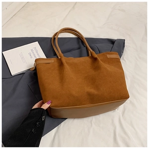Détail du sac cabas en daim caramel avec poignées en cuir et coutures texturées