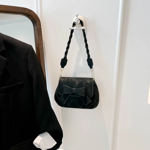 Détail du sac vintage noir avec nœud décoratif et bandoulière en corde tressée