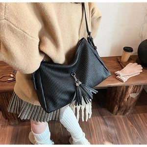 Detailaufnahme der schwarzen plissierten Ledertasche mit Quasten und silbernem Metallring