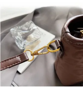 Detailed close-up of golden alloy hardware and fine stitching on dark brown leather bag