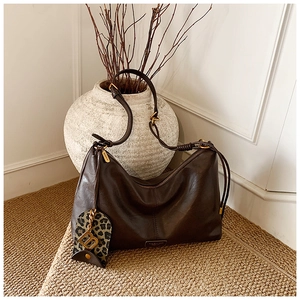 Detail of dark brown leather tote bag with leopard print charm and gold hardware